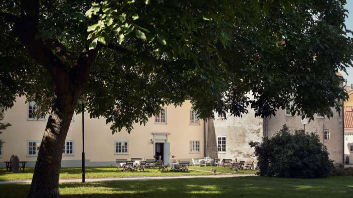Ein Baum steht vor einem Gebäude mit Tisch und Stühlen