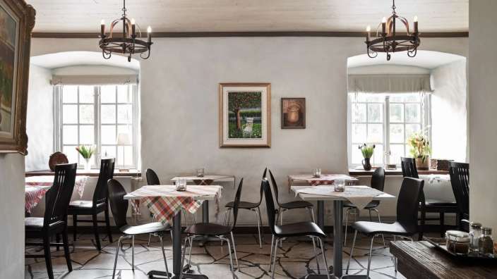 Ein Esszimmer mit Tischen und Stühlen und einem Gemälde an der Wand