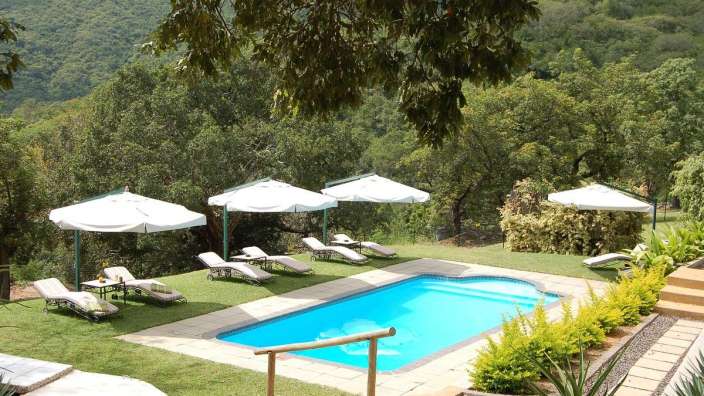 Ein großer Swimmingpool mit weißen Sonnenschirmen und Liegestühlen