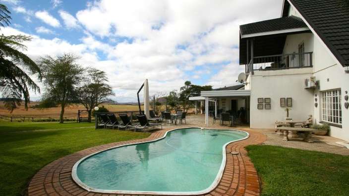 Ein weißes Haus mit einem großen Pool im Garten