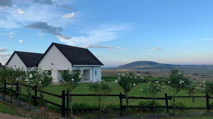 Ein weißes Haus mit einem schwarzen Dach und einem Holzzaun