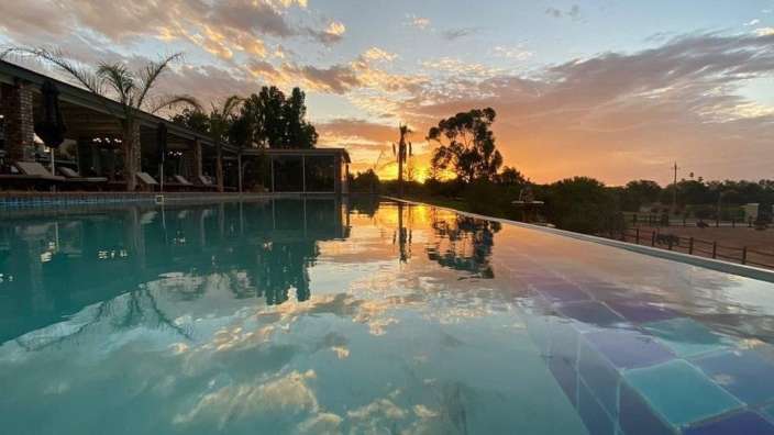 Ein Infinity-Pool mit Sonnenuntergang im Hintergrund