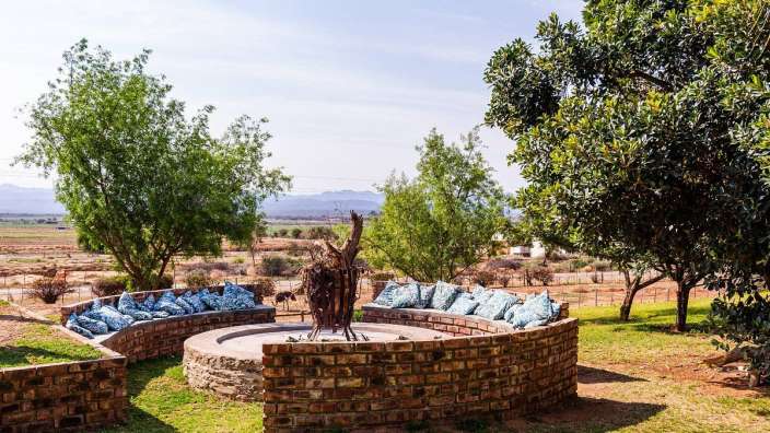 Ein Backsteinfeuerplatz mit blauen Kissen umgeben von Bäumen
