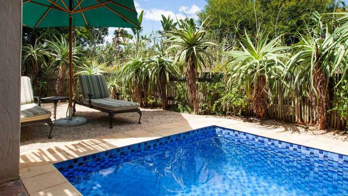 Ein Swimmingpool mit blauen Fliesen und einem grünen Regenschirm