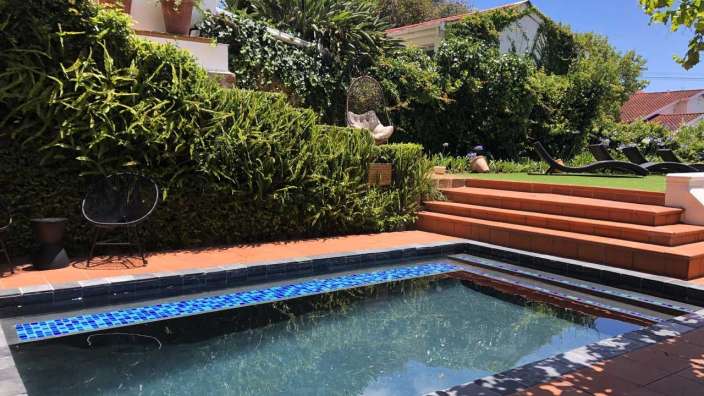 Ein Swimmingpool in einem Garten neben einem Haus