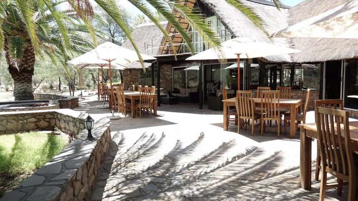 Tische und Stühle auf einer Terrasse mit weißen Sonnenschirmen