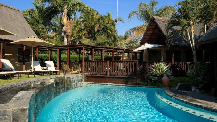 Ein großer Swimmingpool umgeben von Palmen und Liegestühlen