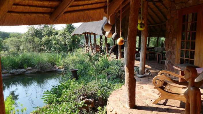 Eine Bank sitzt unter einem Strohdach neben einem Teich