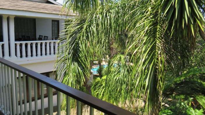 Ein Balkon mit Blick auf einen Pool und Palmen
