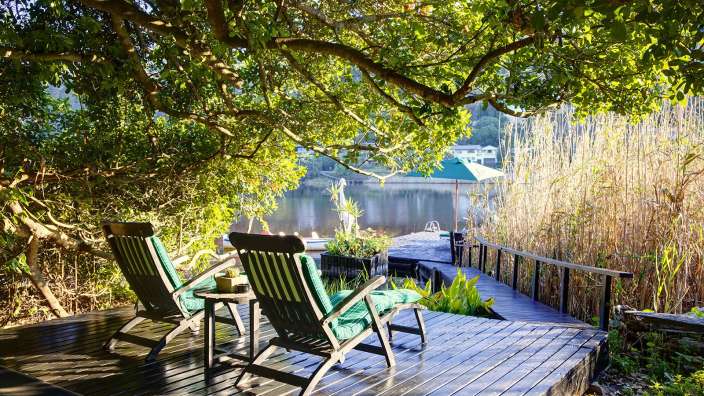 Zwei Stühle sitzen auf einem Holzdeck mit Blick auf einen See