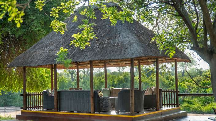 Ein Strohdachzelt mit Couchgarnituren und Stühlen