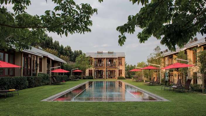 Ein großer Pool mit roten Sonnenschirmen und Stühlen in der Nähe eines großen Gebäudes
