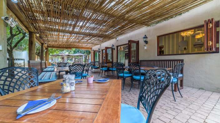 Ein Restaurant mit Holztischen und Stühlen mit blauen Kissen