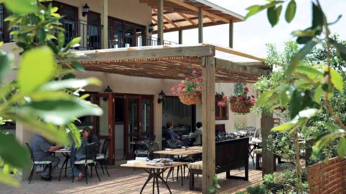 Eine Gruppe von Menschen sitzt an Tischen und Stühlen vor einem Restaurant