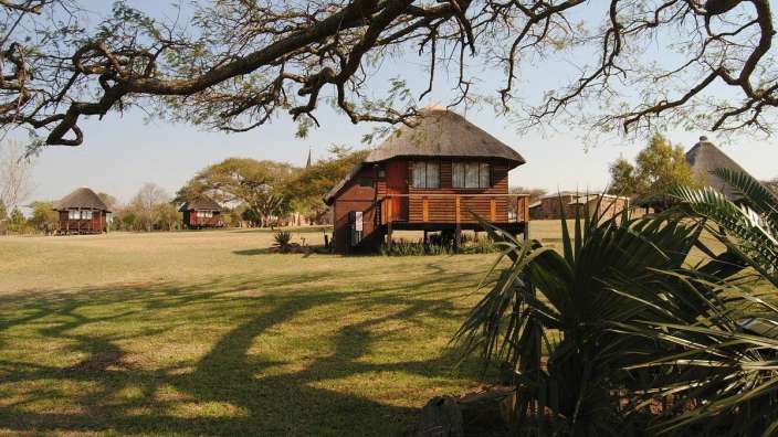 Ein Holzhaus mit Strohdach steht in einem Feld