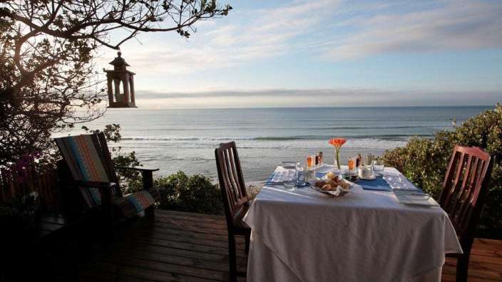 Ein Tisch und Stühle auf einem Deck mit Blick auf das Meer