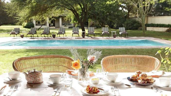 Ein Tisch mit Essen und einer Teekanne darauf steht vor einem Swimmingpool