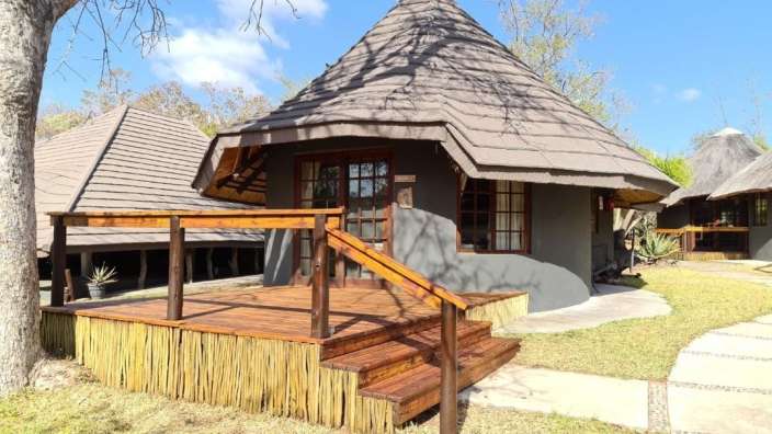 Ein kleines Haus mit einem Strohdach und einem Holzdeck