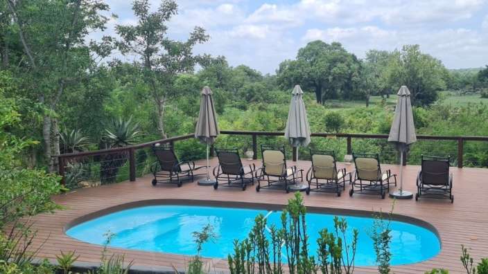 Liegestühle und Sonnenschirme umgeben einen großen Swimmingpool