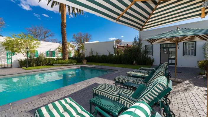 Ein Swimmingpool mit grünen und weißen Stühlen und Regenschirmen