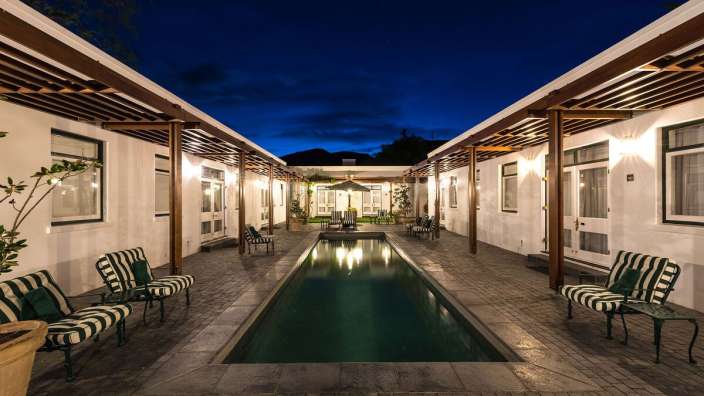 Ein Swimmingpool zwischen zwei Gebäuden mit Stühlen und einem Regenschirm