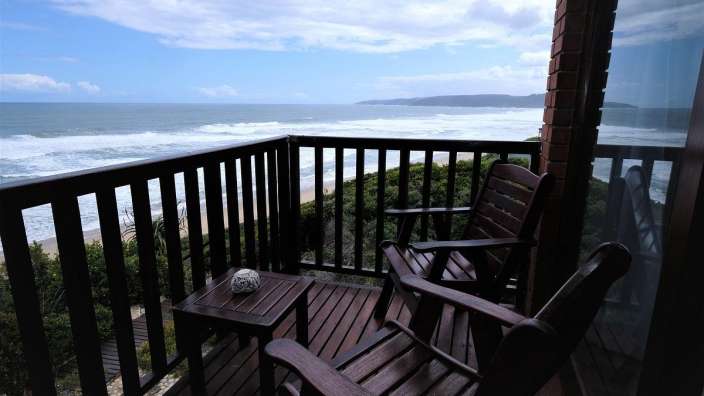 Ein Balkon mit zwei Stühlen und einem Tisch mit Blick auf das Meer