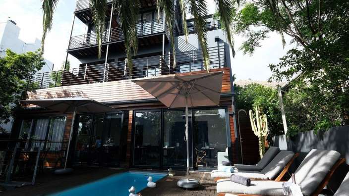 Ein großes Haus mit einem Pool und Liegestühlen davor