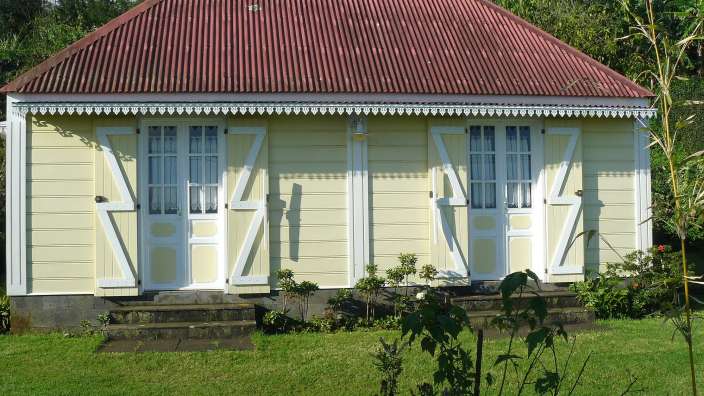 Ein gelbes Haus mit einem roten Dach und weißen Fensterläden