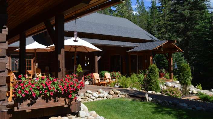 Ein Holzhaus mit roten Blumen und weißen Sonnenschirmen