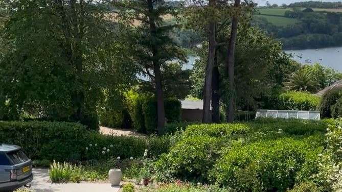 Ein Auto steht in einem Garten mit Blick auf einen See .