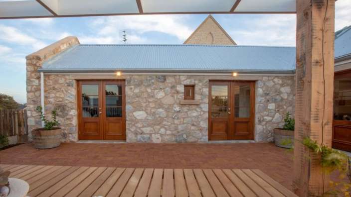 Ein kleines Steingebäude mit einer Holzterrasse davor