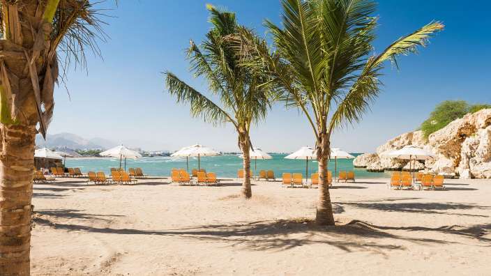 Ein Strand mit vielen Stühlen und Sonnenschirmen
