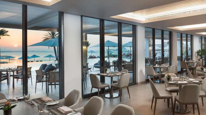Ein Restaurant mit vielen Tischen und Stühlen mit Blick auf das Meer