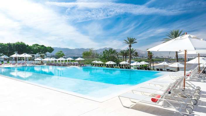 Ein großer Pool mit vielen weißen Sonnenschirmen umgeben