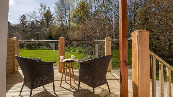 Zwei Stühle und ein Tisch auf einer Terrasse mit einem Buch auf dem Tisch