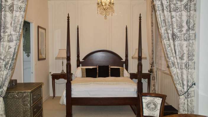 Ein Schlafzimmer mit einem vierposterbett und einem Kronleuchter