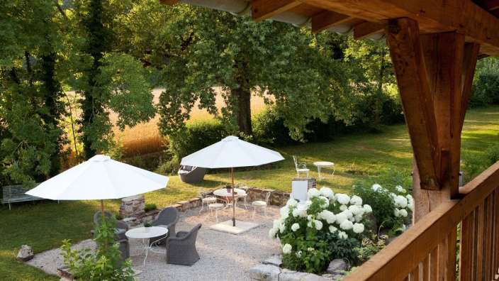 Eine Terrasse mit Tisch und Stühlen und weißen Sonnenschirmen