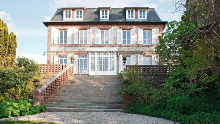 Ein großes Backsteinhaus mit weißen Fensterläden