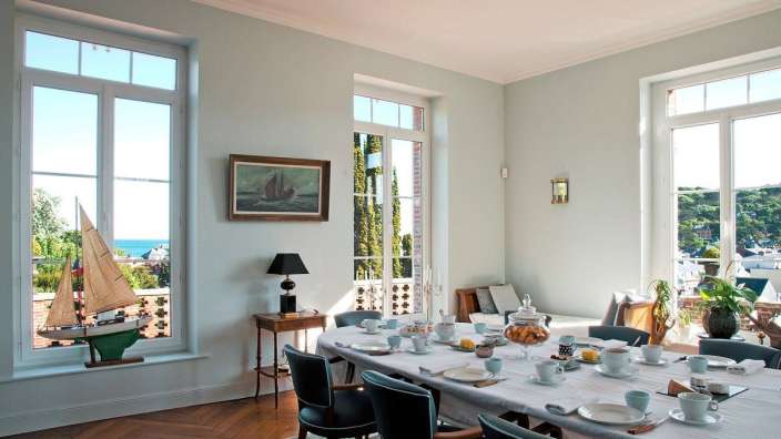 Ein Esszimmer mit einem langen Tisch und vielen Fenstern