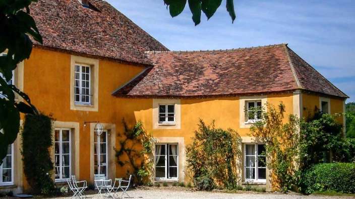 Ein gelbes Haus mit weißen Fenstern und einem roten Dach