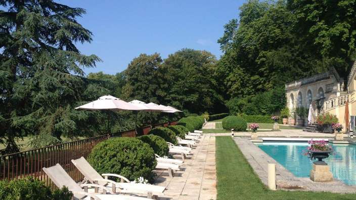 Liegestühle und Sonnenschirme stehen neben einem großen Swimmingpool