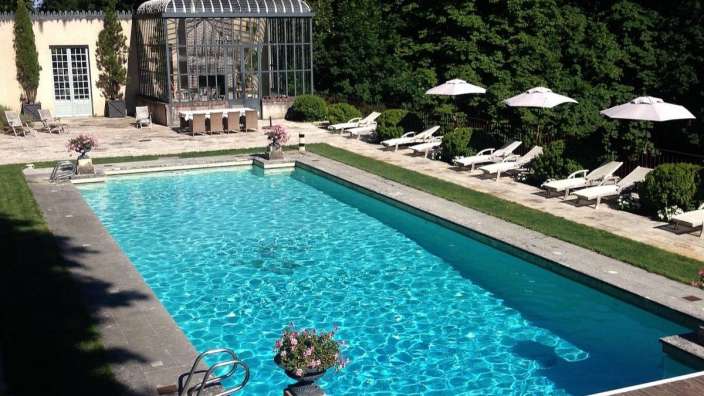 Ein großer Swimmingpool mit Liegestühlen und Sonnenschirmen umgeben