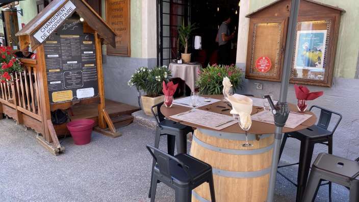Ein hölzerner Tisch mit einem roten Regenschirm vor einem Restaurant