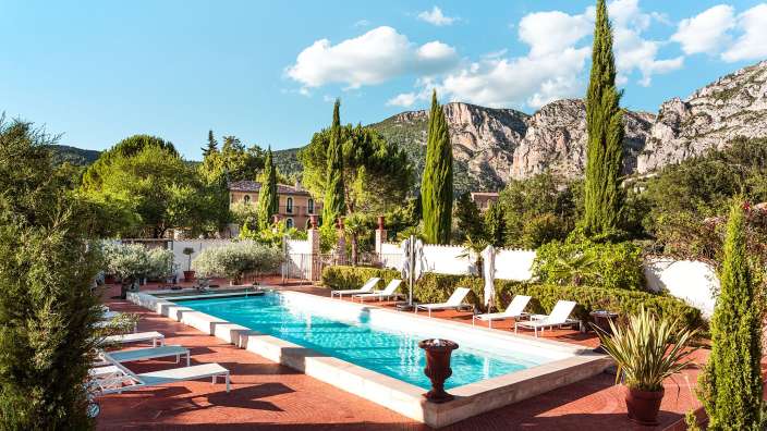 Ein großer Swimmingpool umgeben von Liegestühlen und Bäumen