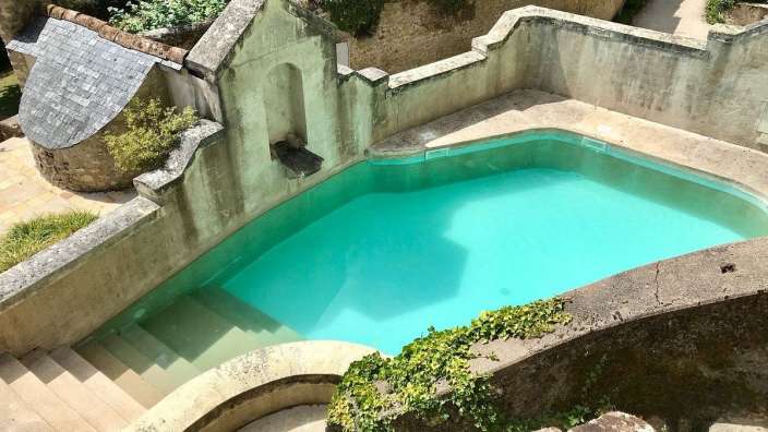 Ein großer Swimmingpool mit einem Steingebäude im Hintergrund