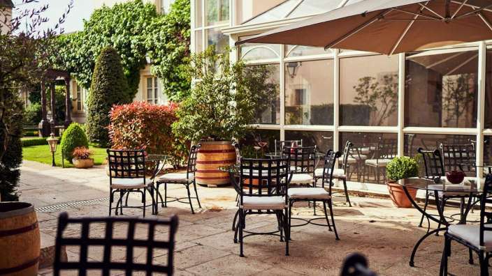 Tische und Stühle auf einer Terrasse mit Sonnenschirmen