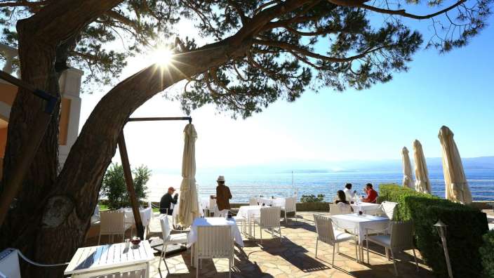 Eine Gruppe von Menschen sitzt an einem Tisch in einem Restaurant mit Blick auf das Meer