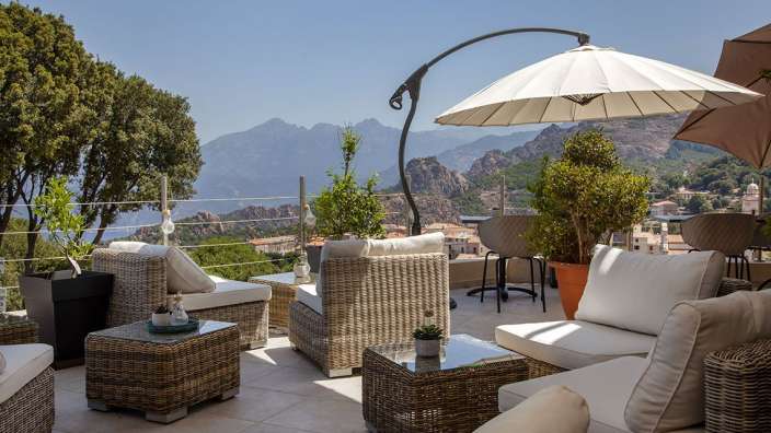 Eine Terrasse mit Möbeln und einem weißen Regenschirm