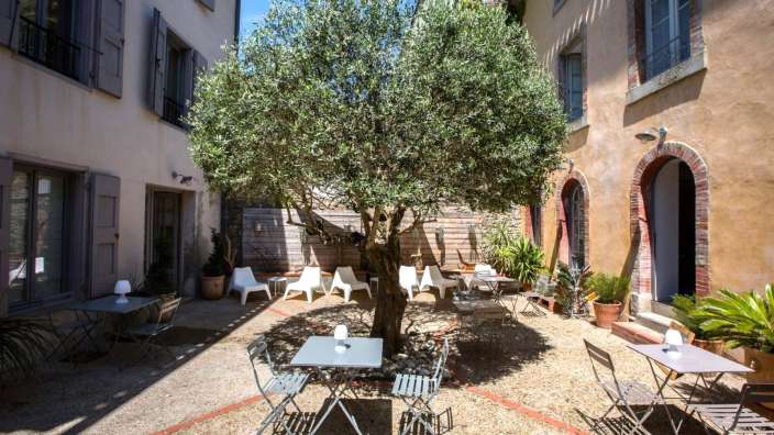 Ein kleiner Hof mit Tischen und Stühlen und einem Baum