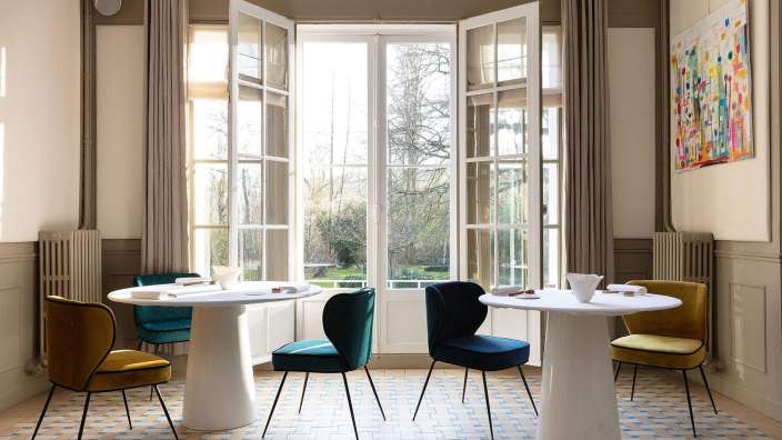 Eine Reihe von Stühlen und Tischen in einem Raum mit einem Gemälde an der Wand